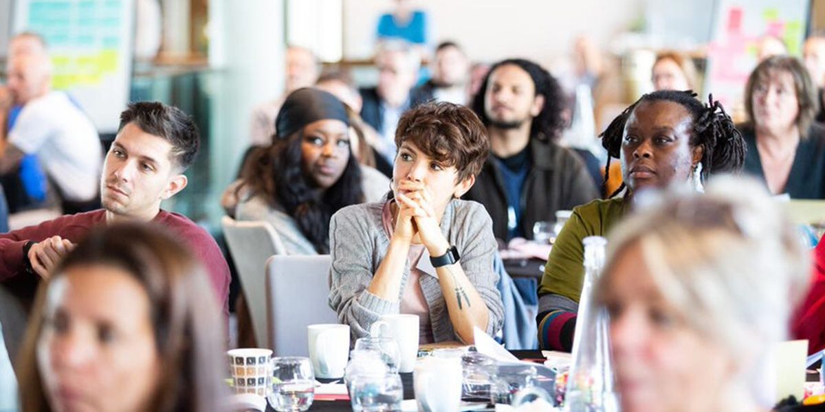 Participants of a conference sitting at their tables while listening to a speech.