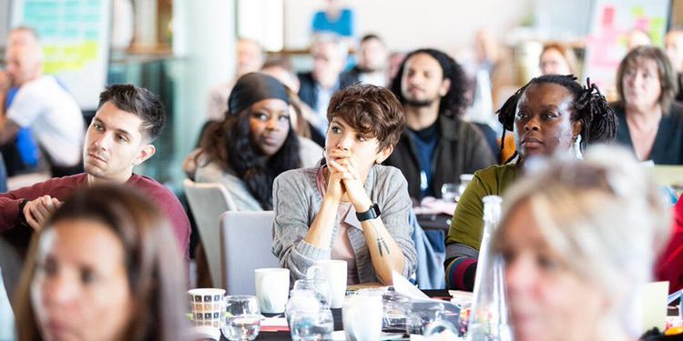 Participants of a conference sitting at their tables while listening to a speech.